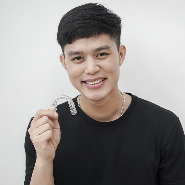 A male patient holding his aligners