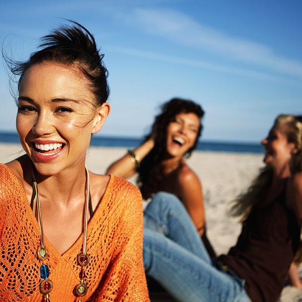 Three women on the beach showing off their new smile after their dental cleaning in Gretna