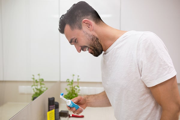 A young man brushing his teeth to prevent periodontal problems
