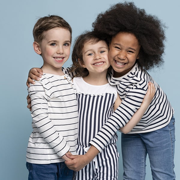 A group of three children smiling and hugging